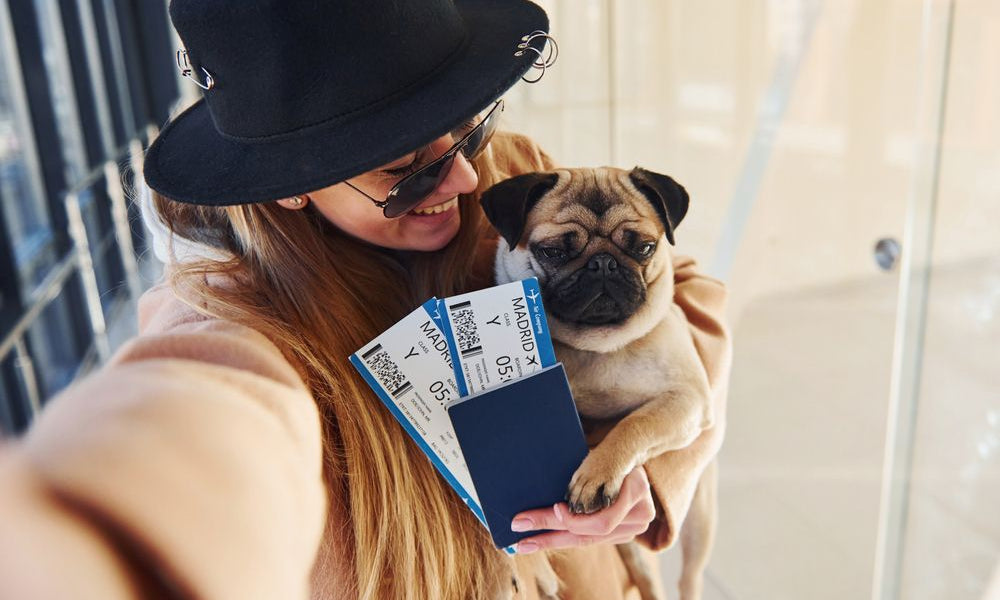 ragazza con in braccio un carlino all’aeroporto 